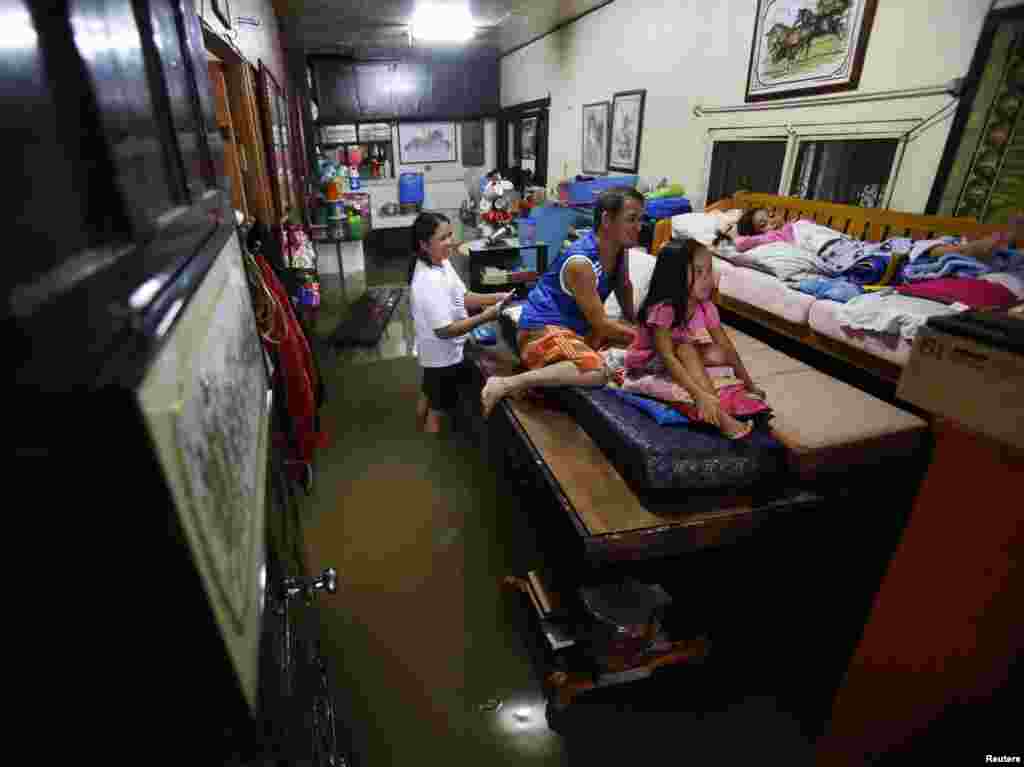 A family watches television inside their flooded house in Bacoor near Manila, August 20, 2013.