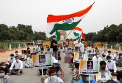 FILE - A police officer heckles a supporter of India's main opposition Congress party as others pay tribute to the Indian army soldiers killed in a border clash with Chinese troops in Ladakh region, at India Gate, in New Delhi.