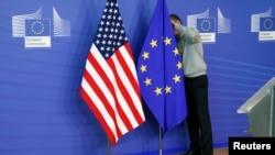 A worker adjusts European Union and U.S. flags at the start of the 2nd round of EU-US trade negotiations for Transatlantic Trade and Investment Partnership at the EU Commission headquarters in Brussels November 11, 2013. REUTERS/Francois Lenoir (BELG