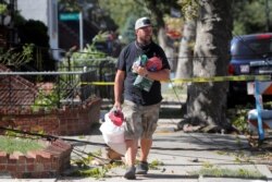 A man carries supplies as he walks over fallen tree limbs and downed power lines in the aftermath of Tropical Storm Isaias in the Sheepshead Bay Area of Brooklyn, New York, Aug. 4, 2020.