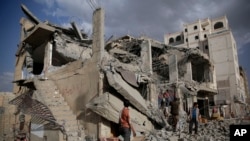 Men inspect a house destroyed by a Saudi-led coalition airstrike in Sana'a, Yemen, Jan. 25, 2016. 