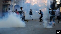 Kashmiri protesters run for cover as Indian police use tear smoke to disperse protesters during a clash in Srinagar, Indian-controlled Kashmir, Oct. 16, 2017. 