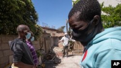 Seorang pria menggunakan rangka tempat tidur sebagai kompor untuk memasak ayam untuk migran lainnya dari Nigeria dan Ghana, di Castel Volturno, dekat Naples, selatan Italia, 27 April 2020. (Foto: AP)