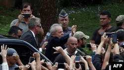 Former Brazilian president Luiz Inacio Lula da Silva (center-waving) is escorted by security personnel upon arrival at Jardim da Colina cemetery, in Sao Bernardo do Campo, Sao Paulo, Brazil, to attend the funeral of his grandson, March 2, 2019.