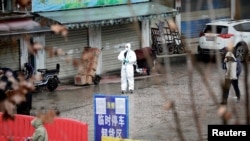 Seorang pekerja dalam pakaian pelindung terlihat di pasar makanan laut yang tertutup di Wuhan, Provinsi Hubei, China, 10 Januari 2020. Pasar tersebut dikaitkan dengan wabah pneumonia yang disebabkan oleh strain baru virus corona. (Foto: Reuters)