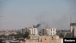 Asap membumbung dekat gedung-gedung menyusul pertempuran hebat antara dua kelompok milisia di Tripoli, Libya (20/7). (Reuters/Hani Amara)