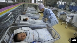 A nurse takes care of newborn babies at a hospital in Hefei, Anhui province April 21, 2011.