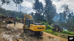 Los aldeanos utilizan maquinaria pesada para buscar entre un deslizamiento de tierra en Yambali, en las Tierras Altas de Papúa Nueva Guinea, el domingo 26 de mayo de 2024.