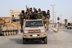 Turkey-backed Syrian rebel fighters ride on a vehicle at the border town of Tel Abyad, Syria, Oct. 14, 2019.