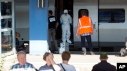 People wait for a train in the foreground as members of a police forensics team take part in an investigation next to a Thalys train on the platform at Arras train station, northern France, Aug. 22, 2015. 