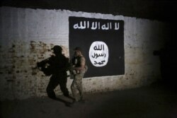 FILE - In this March 1, 2017 photo, an Iraqi soldier inspects a tunnel, adorned with an Islamic State group flag. According to the U.S. Treasury Department, the Islamic State has an estimated $100 million available in cash reserves.