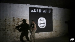 FILE - In this March 1, 2017 photo, an Iraqi soldier inspects a tunnel, adorned with an Islamic State group flag. 