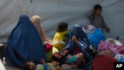 FILE - Afghan refugee families wait at the office of United Nations High Commissioner for Refugees to register to go back to Afghanistan, in Peshawar, Pakistan, April 27, 2017.