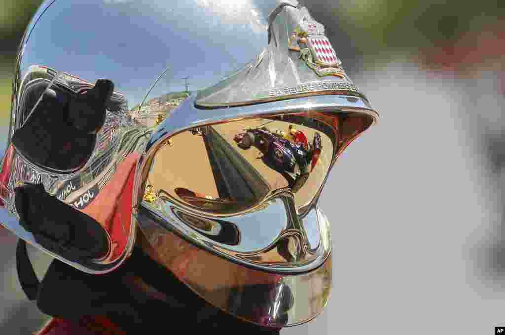 Pembalap Red Bull Sebastian Vettel dari Jerman tampak pada helm petugas pemadam kebakaran di pit saat sesi latihan di arena balap Monaco.