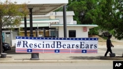 FILE - A banner hangs in Blanding, Utah, May 8, 2017. U.S. Interior Secretary Ryan Zinke visited Blanding that morning, where he took a helicopter tour with Utah Gov. Gary Herbert to see Bears Ears National Monument on lands considered sacred to a coalition of five tribes.