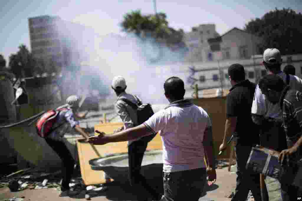 Supporters of ousted Egyptian President Mohamed Morsi react to an explosion of unknown origin and throw stones at police officers nearby, during a protest in Cairo University, Giza, Egypt, July 5, 2013.