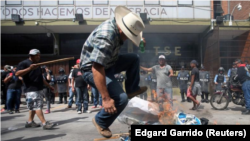 Un seguidor del candidato opositor a la presidencia de Honduras Salvador Nasralla salta sobre imágenes en llamas del mandatario y candidato Juan Orlando Hernández, mientras espera lso resultados oficiales de la elección Tegucigalpa, Honduras, 29 de noviem