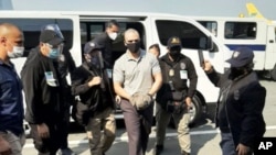 In this photo provided by the Philippines' Bureau of Immigration Public Information Office, U.S. Marine Lance Cpl. Joseph Scott Pemberton, center, arrives at the airport before boarding a U.S. military plane in Manila, Philippines, Sept. 13, 2020.