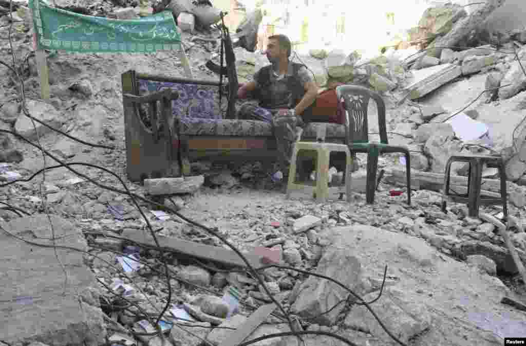 Seorang anggota Tentara Pembebasan Suriah duduk di sofa di sebuah jalan di daerah Salaheddine, Aleppo (30/7). 