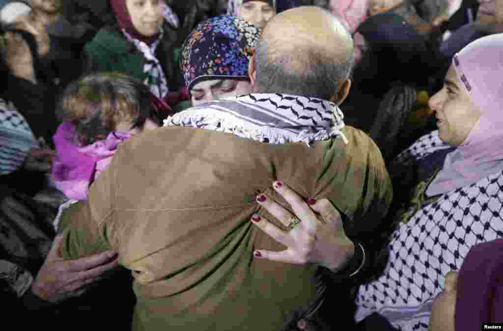 A prisoner released from an Israeli prison (C, back to camera) is welcomed by relatives in Ramallah, West Bank, Dec. 31, 2013. 
