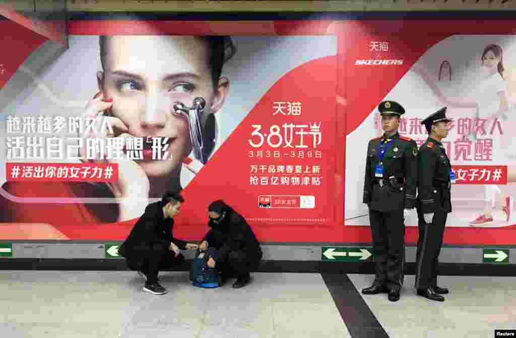 武警站在北京地铁站的阿里巴巴电子商务平台天猫的3·8女王节广告前面。(2018年3月7日)。广告说:活出自己的理想“型”和女子力。两位警察站姿端正挺拔,各自监视一个方向。