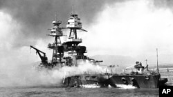 FILE - In this file image provided by the U.S. Navy, crewmen of the USS Nevada still fight flames on the battleship, battered in the Japanese aerial attack on Pearl Harbor on Dec. 7, 1941. 