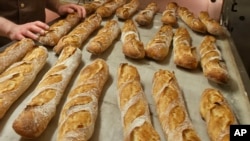 Baguettes are seen as they come out of the oven of the bakery La Parisienne in Paris, Friday, March 18, 2016. A bakery in a small town southwest of Paris has been fined for staying open seven days a week. 