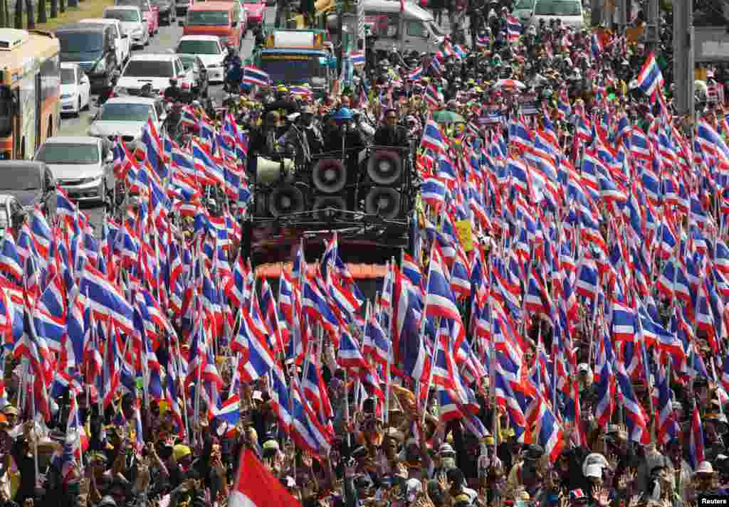 Anti-government protesters hold Thai national flags as they march toward the Department of Special Investigation (DSI) in Bangkok. The Thai baht plumbed its lowest level in almost four years as a political crisis grew more intractable.