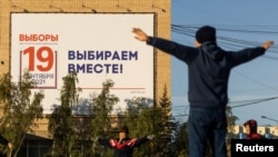 Seorang warga tampak melakukan olahraga di depan papan iklan yang mengumumkan pemilu parlemen di Rusia yang terpasang di wilayah Yakutsk pada 7 September 2021. Pemilu parlemen di Rusia akan berlangsung mulai 17 September 2021. 