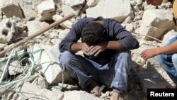 Seorang pria menangis berduka karena kehilangan kerabatnya dalam serangan udara di daerah pemberontak Aleppo, Suriah (11/10). (Reuters/Abdalrhman Ismail)
