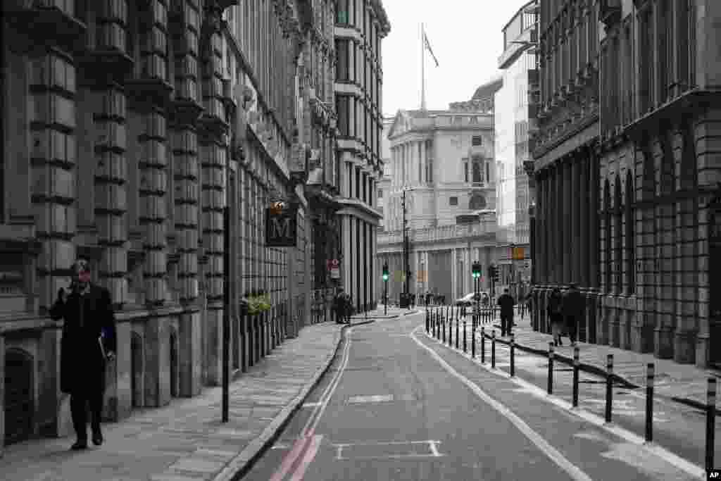 A man talks on the phone while walking in an empty street in the financial district, known as The City, in London. Many people will re-start working from home as the British government warns the rapid spread of omicron "adds additional and rapidly increasing risk to the public and health care services."