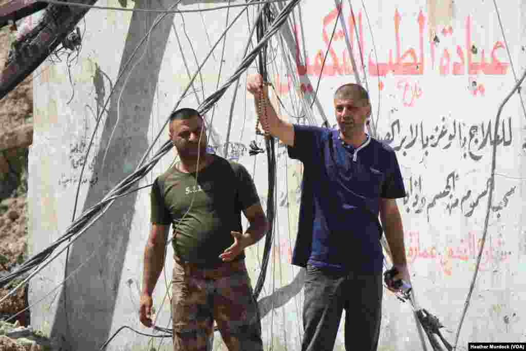 Hazzam Abdulghani holds up prayer beads he finds on the body, cursing IS and saying he knows now it is his nephew in Mosul, Iraq, June 15, 2017.