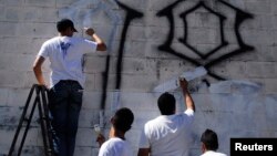 Miembros de las pandillas borran unos "grafitis" que ellos mismo pintaron como muestra del compromiso en el proceso de paz en El Salvador.