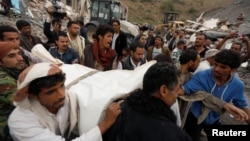 People carry the body of a woman they recovered from under the rubble of a house destroyed by a Saudi-led airstrike in Sanaa, Yemen, Aug. 25, 2017. 