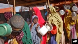 FILE - Women who fled drought queue to receive food at a camp for internally displaced persons, in the Daynile neighborhood on the outskirts of the capital Mogadishu, Somalia, May 18, 2019. 