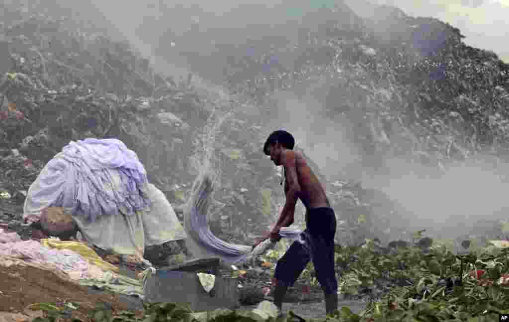 Seorang dhobi, atau binatu, Bangladesh mencuci pakaian di dekat tempat pembuangan sampah di tepi Sungai Buriganga di ibukota Dhaka.
