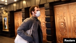 Seorang pria dengan masker berjalan melewati teater yang tutup setelah diumumkan bahwa pertunjukan Broadway akan membatalkan pertunjukan karena corona di New York, AS, 12 Maret 2020. (Foto: Reuters/Mike Segar)