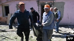 Чоловіки виносять тіло загиблого внаслідок російської атаки, Харків, 30 квітня 2024. SERGEY BOBOK / AFP