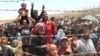 FILE - Syrian refugees gather at the Turkish border as they flee intense fighting in northern Syria between Kurdish fighters and Islamic State militants in Akcakale, southeastern Turkey, June 15, 2015.