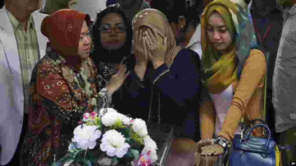 A relative weeps during the handover of the body of Hayati Lutfiah Hamid, one of the victims of AirAsia Flight 8501, to her family at the police hospital in Surabaya, East Java, Indonesia, Jan. 1, 2015.