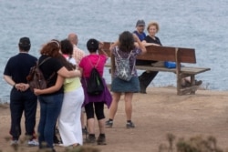 Tourists wait in line to sit on a bench on a cliff overlooking the Cantabrian sea in Loiba, northwestern Spain, Aug. 2, 2020.