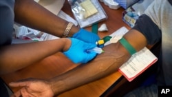 Prélèvement de sang sur un patient en essai clinique pour le vaccin test AstraZeneca dans un établissement hospitalier en dehors de Johannesburg, Afrique du Sud, le 30 novembre 2020.