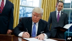 Presiden Amerika Serikat Donald Trump ketika menandatangani surat keputusan presiden untuk mundur dari Perjanjian Kemitraan Trans Pasifik yang beranggotakan 12 negara dan disetujui pada masa pemerintahan Obama, di Ruang Oval, Gedung Putih, Washington, 23 Januari 2017.