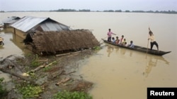 Flood-affected local residents move to safer places on a boat next to their damaged huts after heavy rains at Jajimukh village in the northeastern Indian state of Assam June 27, 2012. Incessant heavy rains in northeast India have caused massive flooding a