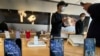 In this photo taken Wednesday, Feb. 19, 2020, staff chats with customers at an apple store in Beijing. Factories that make the world's smartphones, toys and other goods are struggling to reopen after a virus outbreak idled China's economy. But even…