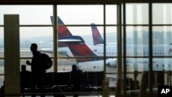 ARCHIVO - Una persona camina por la terminal mientras los planos permanecen en las puertas del Aeropuerto Nacional Ronald Reagan de Washington en Arlington, Virginia, el miércoles 11 de enero de 2023. AP