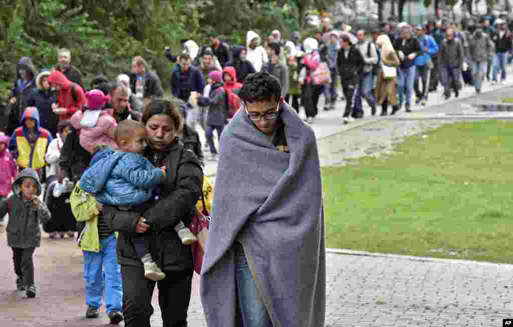 Para migran dari stasiun kereta api utama di Dortmund, Jerman, berjalan menuju gedung tempat mereka dikumpulkan (6/9). (AP/Martin Meissner)