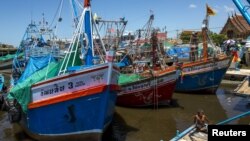 A fisherman man sits on a pier near docked fishing boats at a port in Thailand July 1, 2015. Thai fishermen went on strike to protest regulations aimed at clamping down on illegal fishing. 