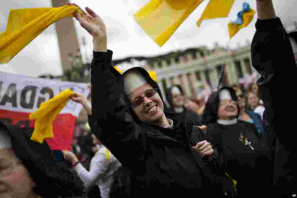 Nuns wave as Pope Francis is driven through the crowd after presiding over a ceremony in St. Peter's Square at the Vatican, April 27, 2014.