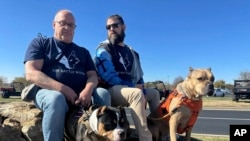 Retired Army First Sgt. Timothy Siebenmorgen, left, and retired Marine Corps Cpl. Mark Atkinson sit with their service dogs, Rosie and Lexi on Nov. 7, 2024, in Kansas City, Kan., during a group training session.